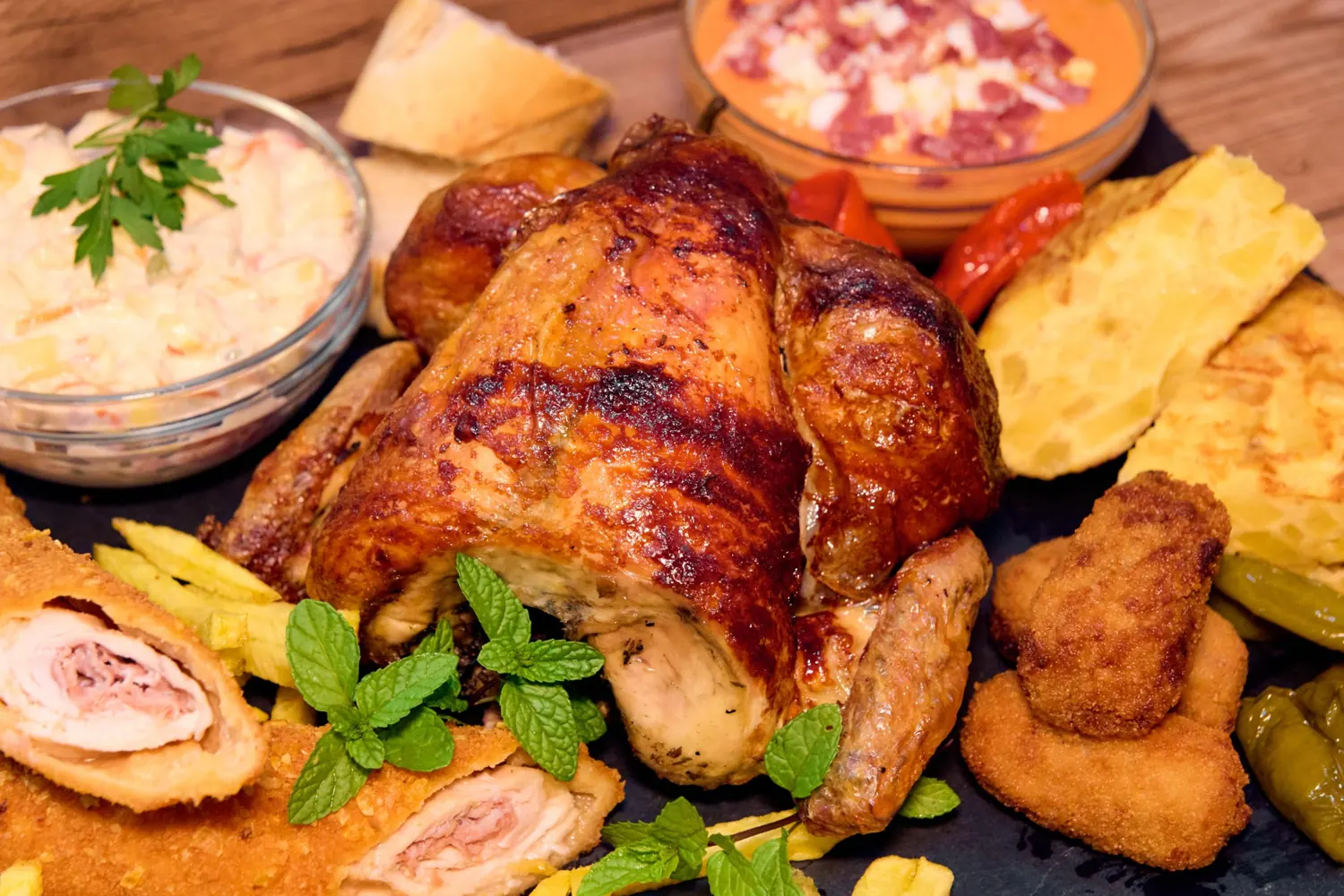 Primer plano de pollo asado con flamenquín, croquetas y tortilla
