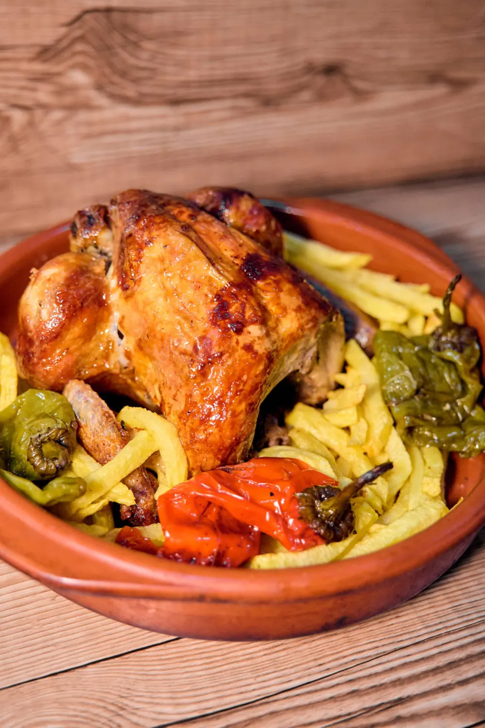 Pollo asado con patatas y pimientos en cazuela de barro